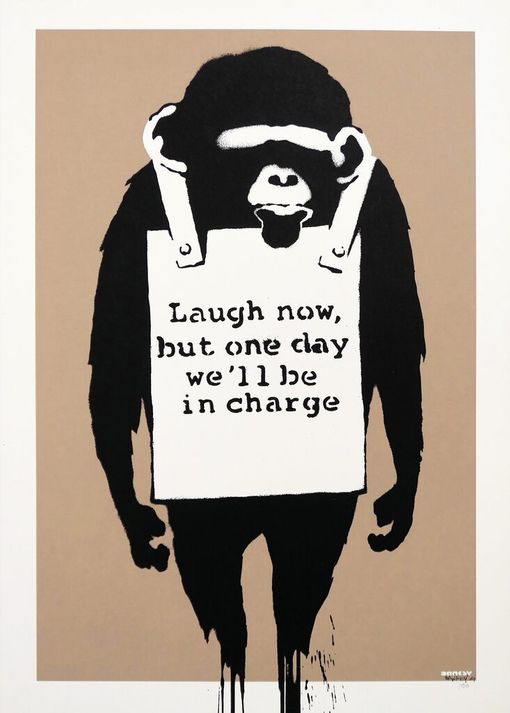 Un singe noir se tient debout, les bras ballants, portant un panneau publicitaire blanc avec l'inscription « Laugh now, but one day we'll be in charge » sur fond marron.