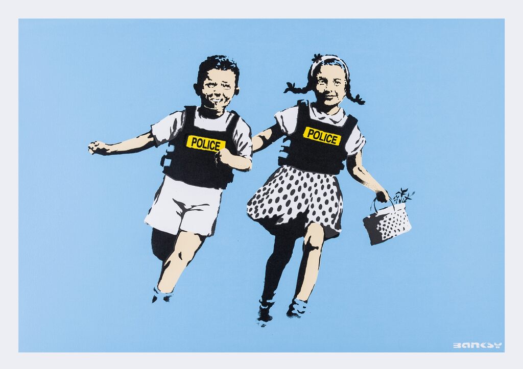 Two smiling children holding hands in black police vests against pale blue.