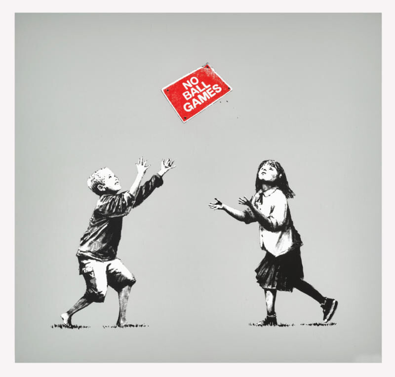 Two black-and-white children tossing a red no ball games sign against grey-green.