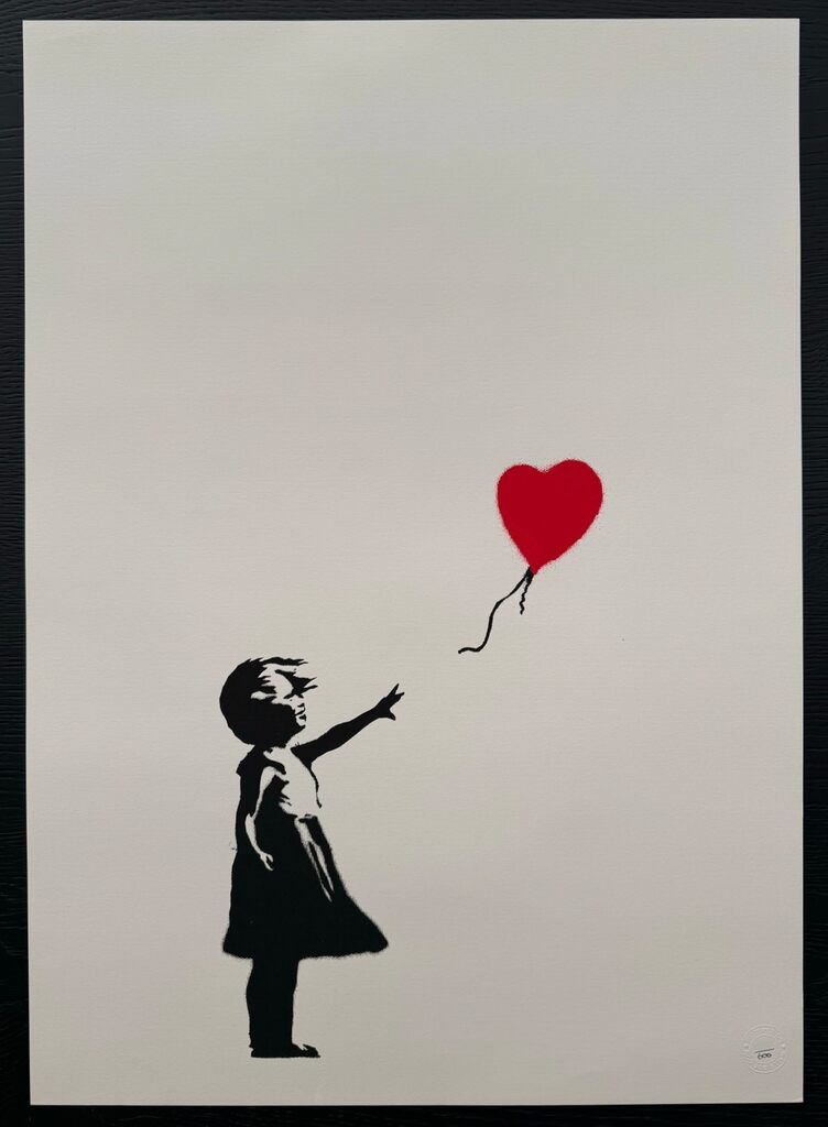 Uma menina em preto e branco está de pé com um braço estendido; um balão vermelho em forma de coração flutua acima e à sua direita, com o cordão solto longe de sua mão.