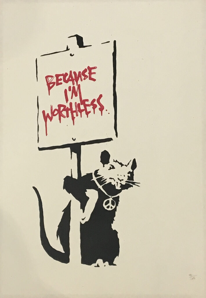 Rat noir portant un collier avec un symbole de paix et tenant une pancarte sur laquelle est écrit « Because I'm worthless » en rouge.