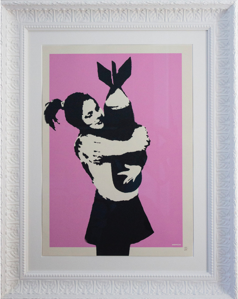 Girl hugging a finned bomb on pink inside an ornate white frame.