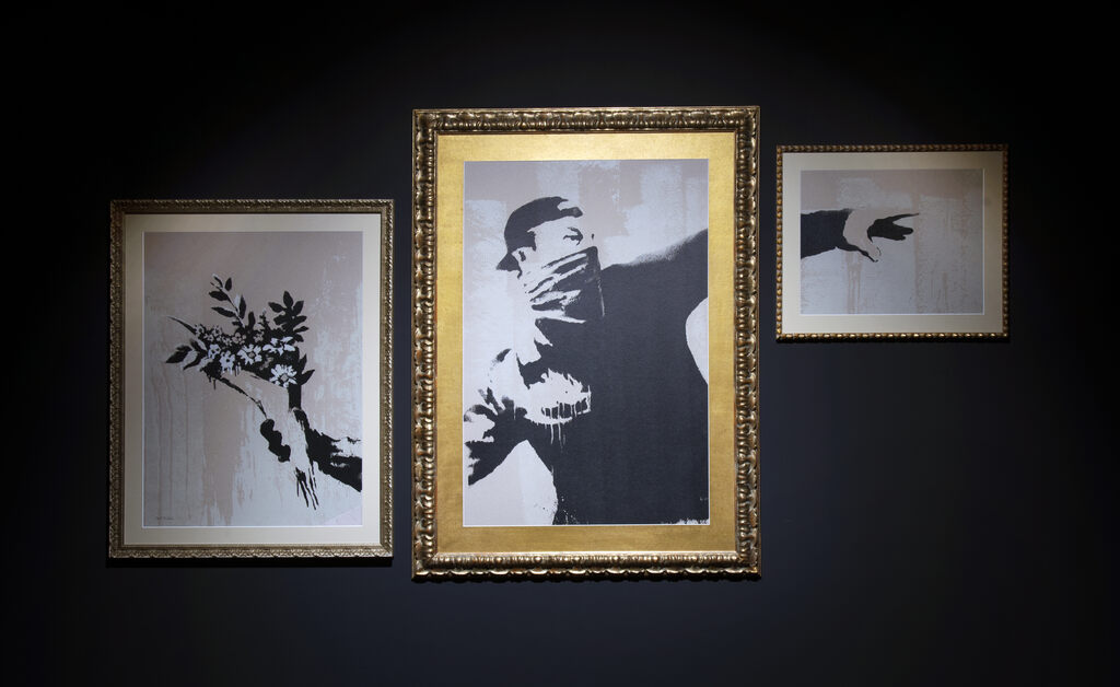 Drie ingelijste delen van een gemaskerde bloemenwerper hangen aan een donkere muur.