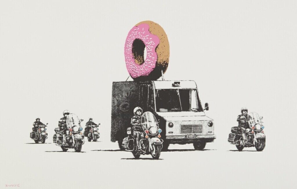Scorta di motociclette attorno a un furgone che trasporta una gigantesca ciambella con glassa rosa.